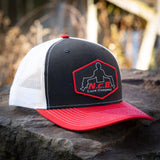 A black/white/red NCB patch style snapback hat positioned on a rock